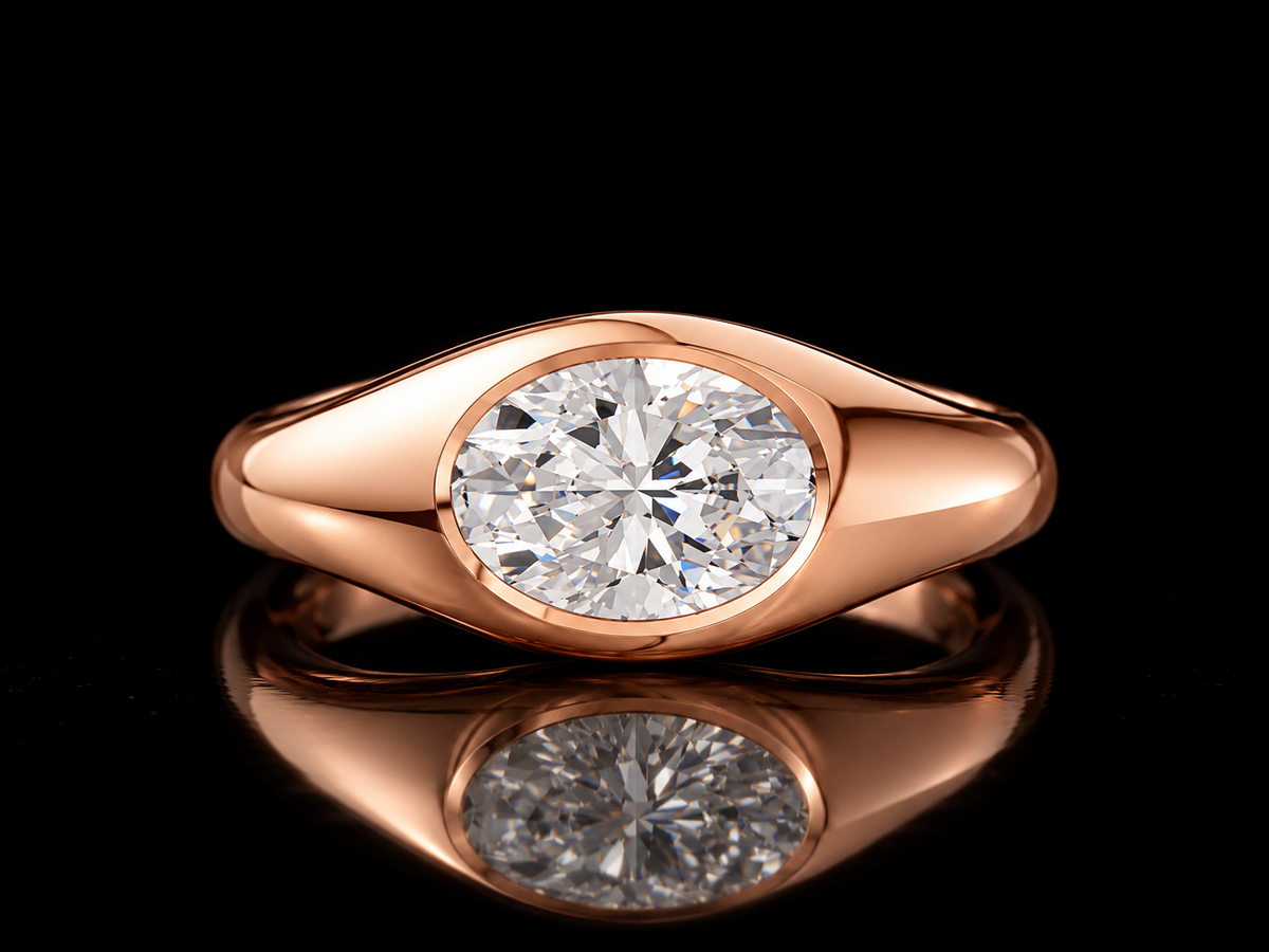 East-West oval diamond signet ring in rose gold standing on black floor with reflection