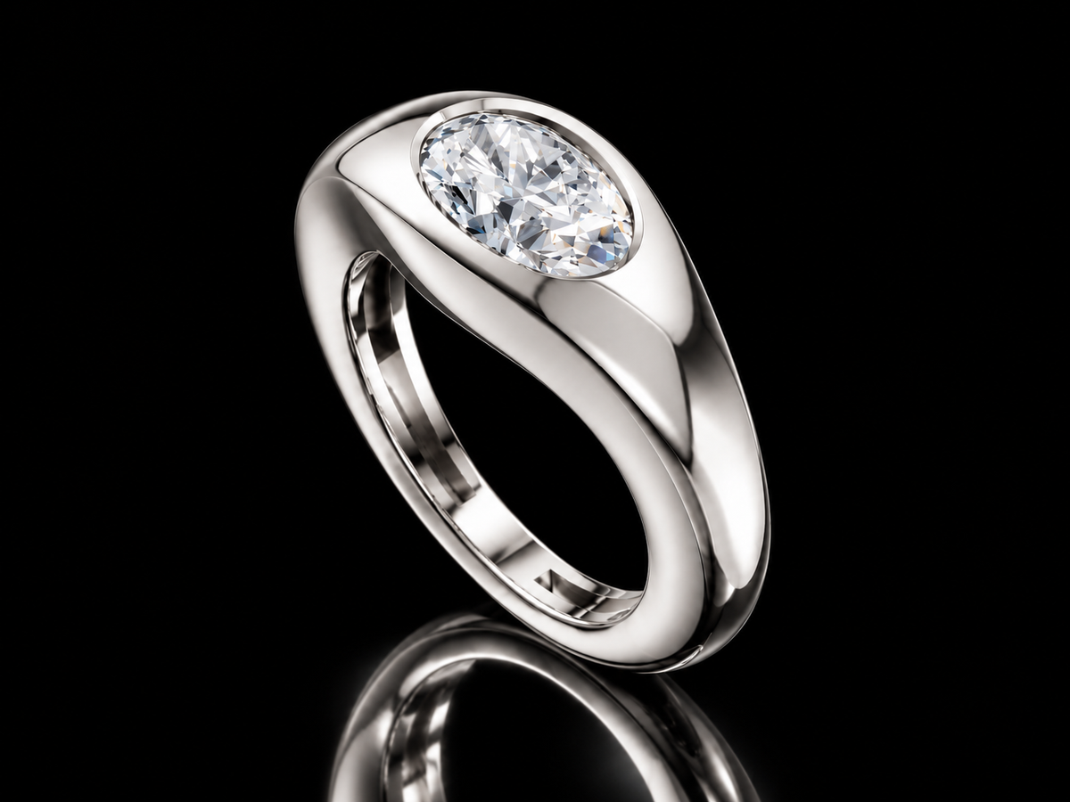 East-West oval diamond signet ring in white gold standing on black floor with reflection